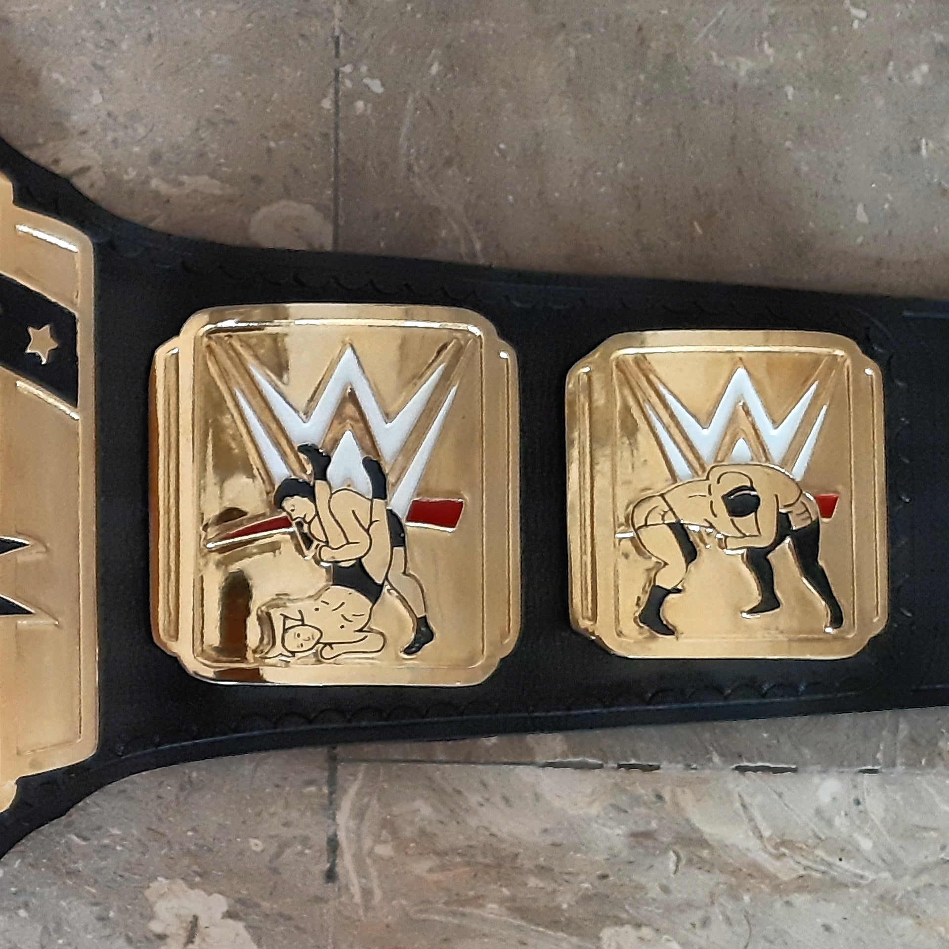 WWE championship belt with gold buckle on a stone surface